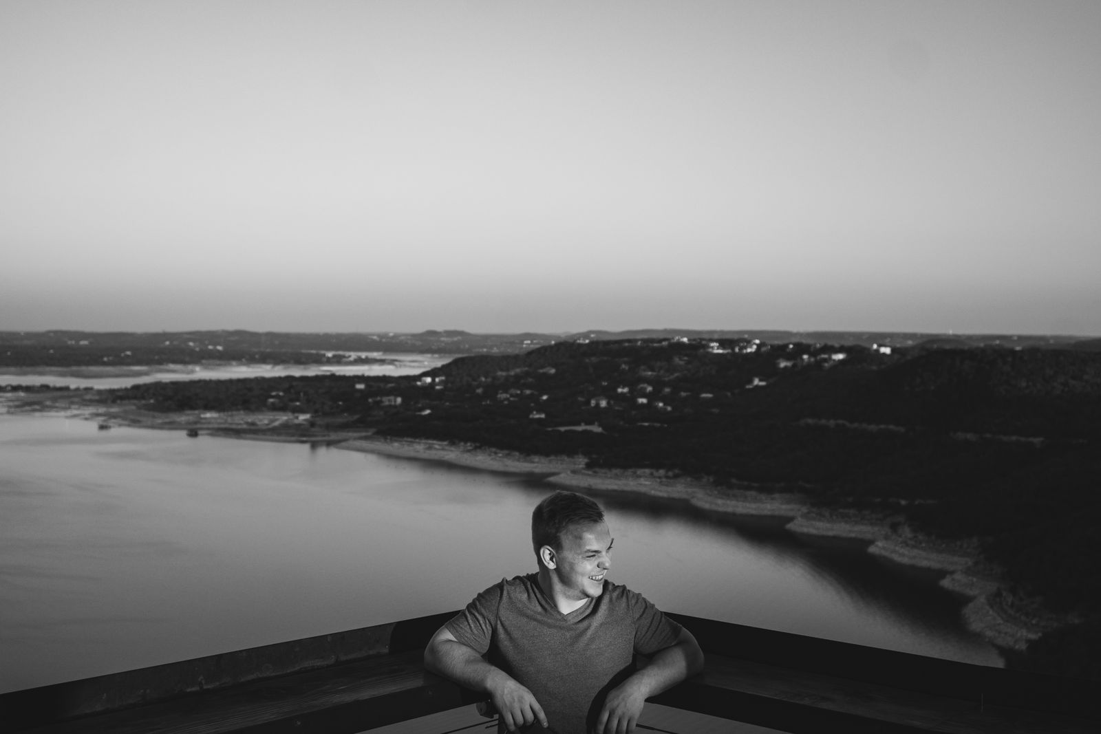 A black and white photo of a man with a Lake Travis behind him
