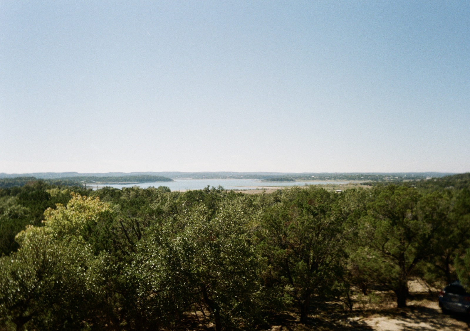 Canyon Lake in the distance, with some trees and greenery in the foreground