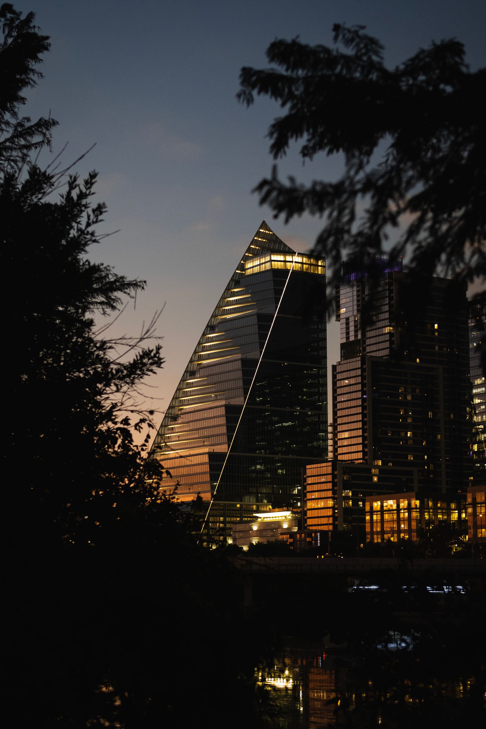 A tall, sail-like building in downtown Austin reflecting an orange glow